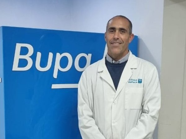 Dr. Mario Ariel Mut Hidalgo frente a un cubo Bupa.