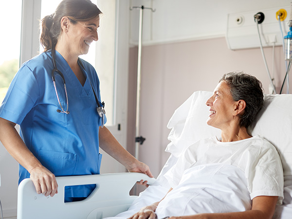 Especialista de la salud sonriendo a paciente acostado en un ambiente hospitalario.